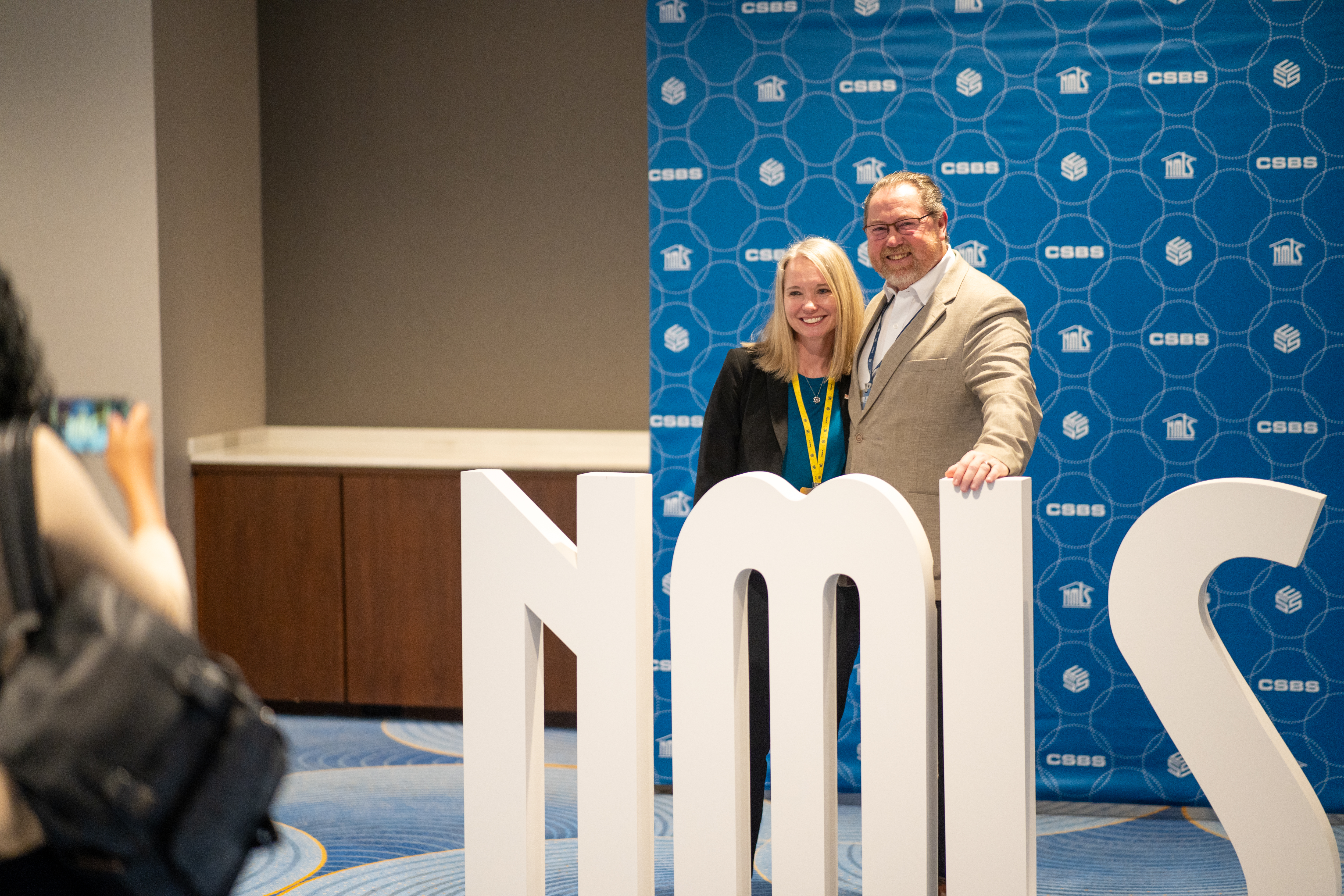 people standing behind NMLS sign